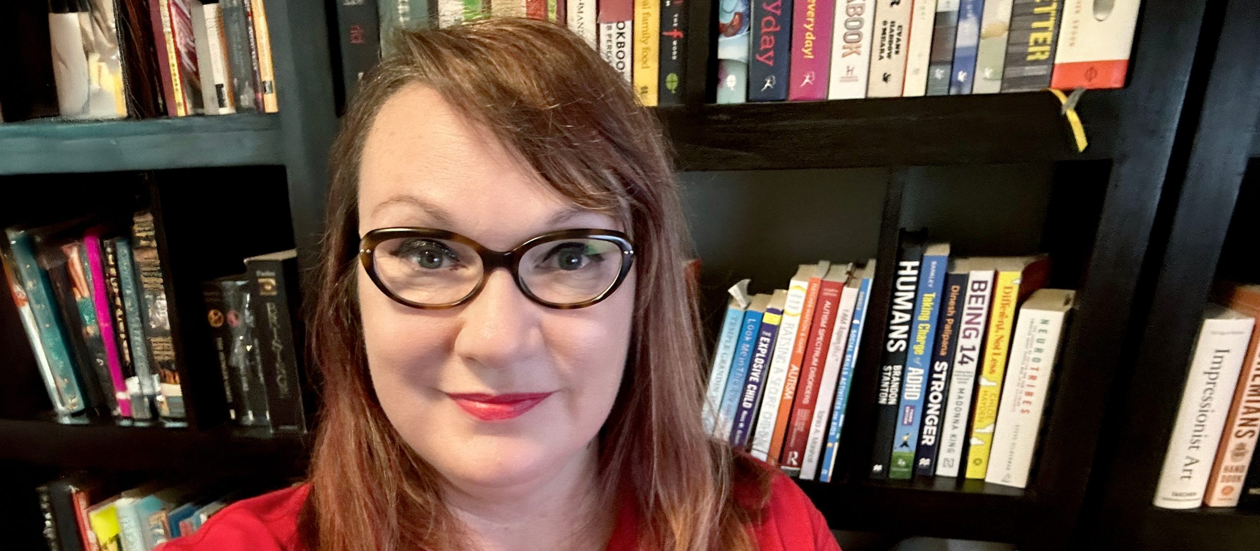 Dee smiling in front of a bookcase