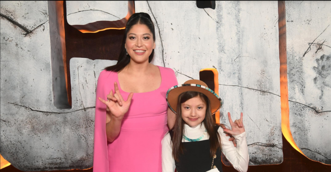 Alaqua Cox and child getting their photo taken at the Echo premier doing the ASL sign for "I love you".