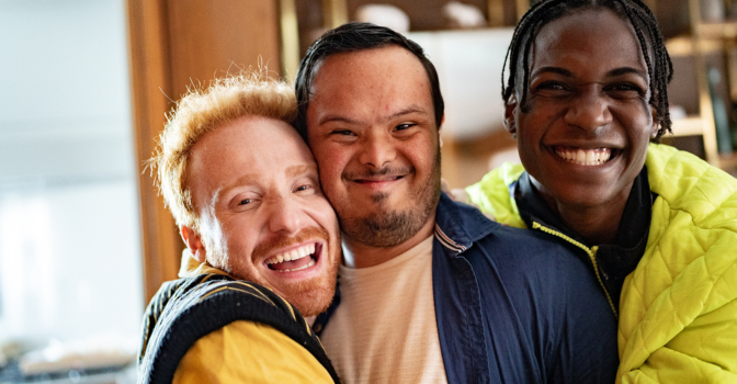 Young person with disability being embraced 2 friends.