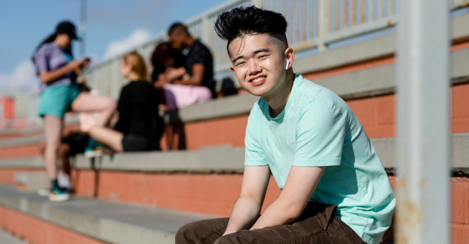 Young boy sitting in the stands, wearing earphones.