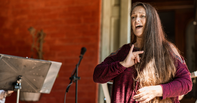 woman standing in front of band interpreting in sing language.