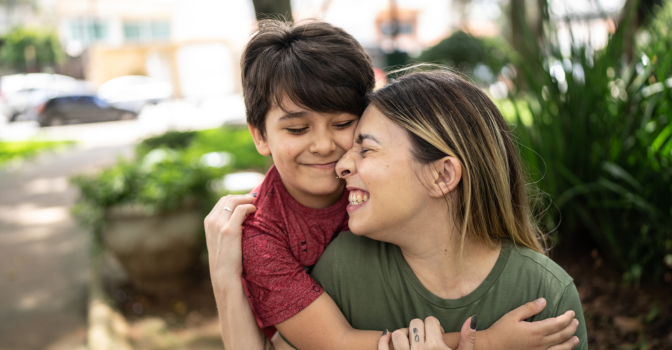 Mother and young son embracing in a garden smiling