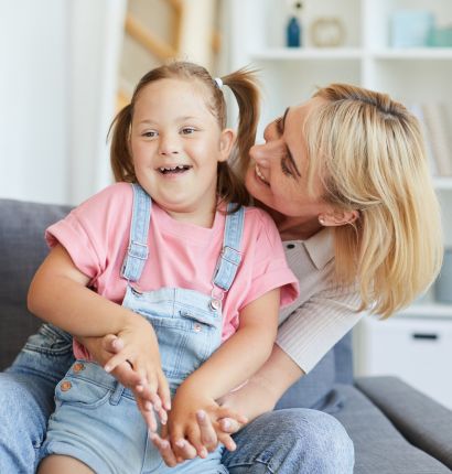 Mother looking intently at her young daughter who is sitting on her lap