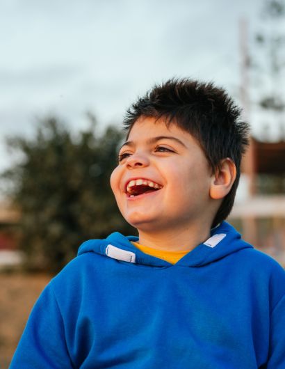 Adolescent boy wearing a blue sweater laughing