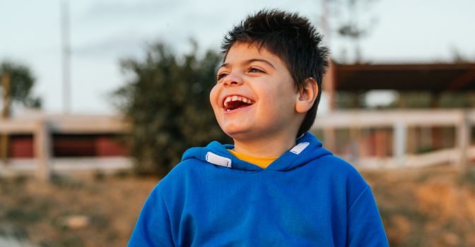 Adolescent boy wearing a blue sweater laughing