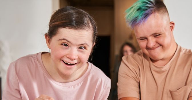Girl laughing at camera next to a boy smiling happily