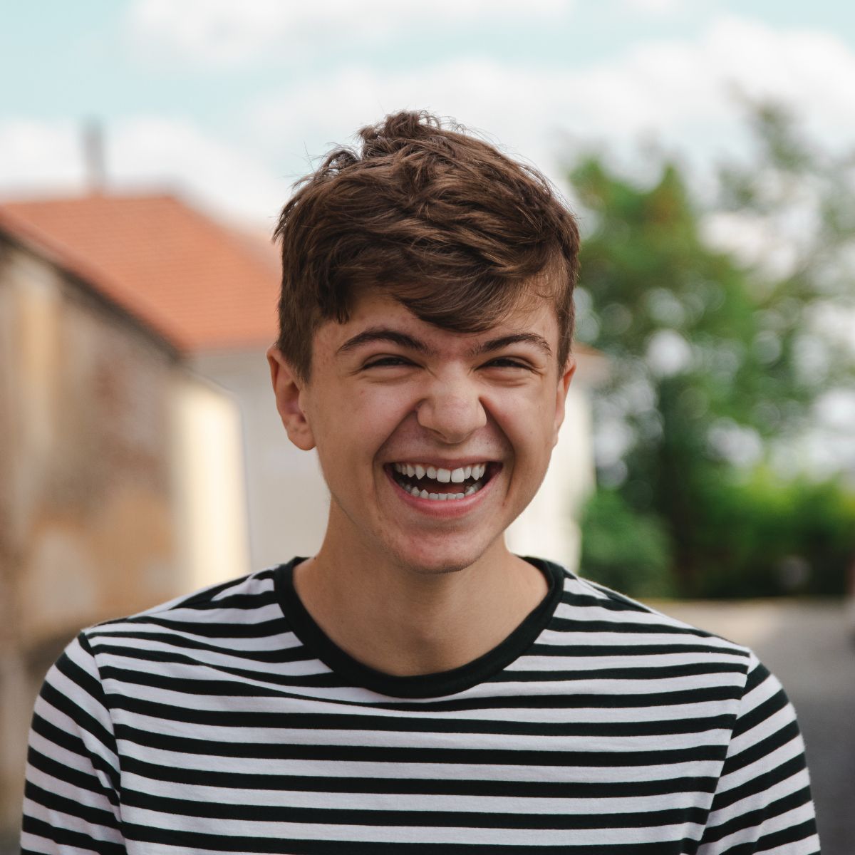 Adolescent boy wearing a black and white striped t-shirt laughing