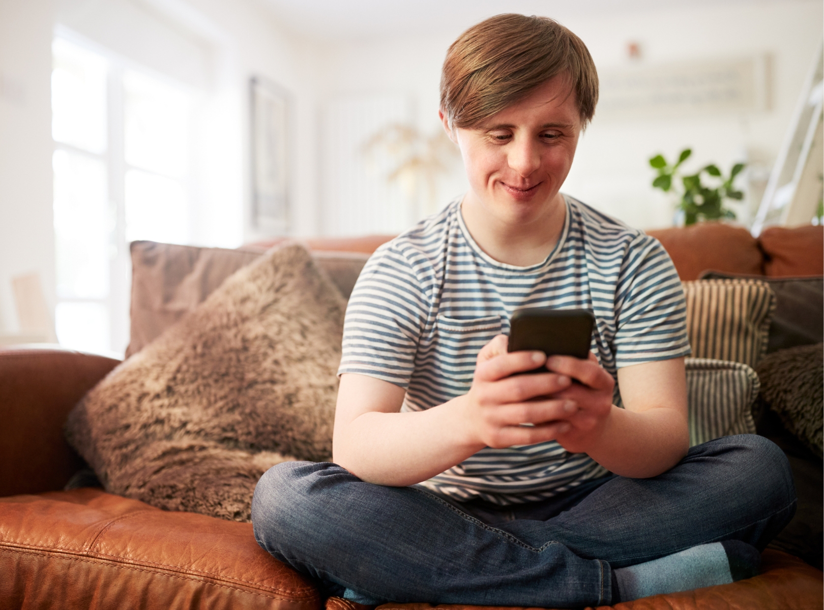 Person sitting with crossed legs on a couch looking at their phone